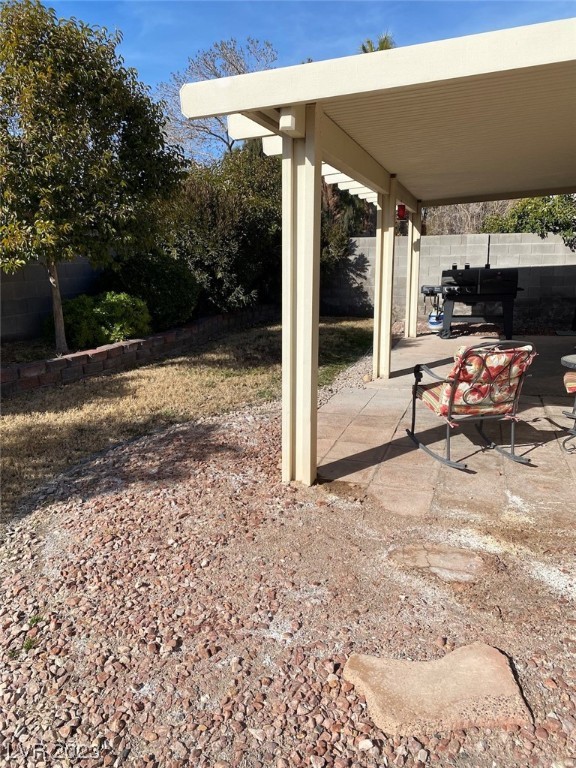 Backyard patio with a covered seating area, patterned rocking chair and barbecue grill.