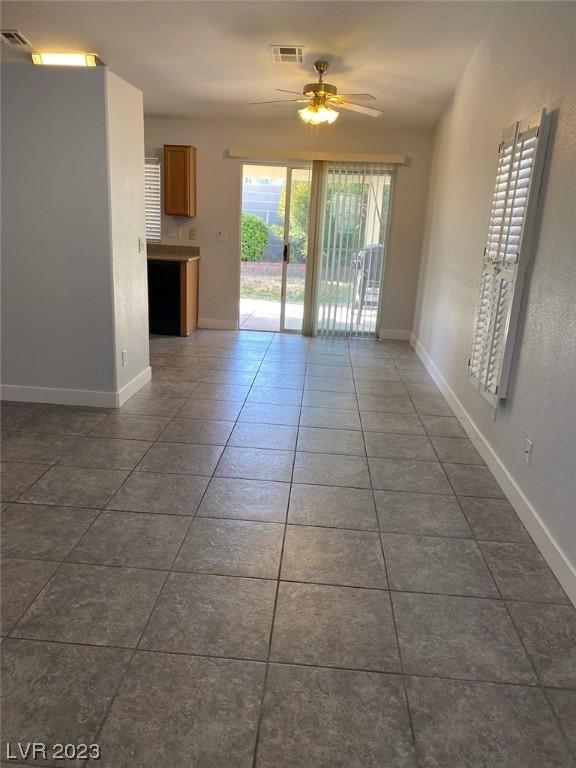Vacant tiled room with a ceiling fan and sliding glass doors opening to a patio.