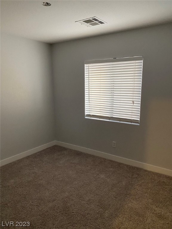 Empty carpeted room with gray walls and a window fitted with closed blinds.