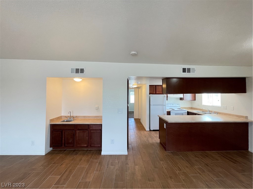 Unfurnished kitchen with dark wood cabinets, a breakfast bar, white appliances, and wood-look tile flooring.