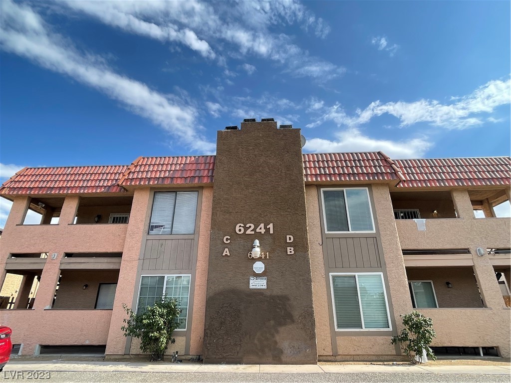 Two-story stucco condominium building with a red tile roof and central tower marked 6241.