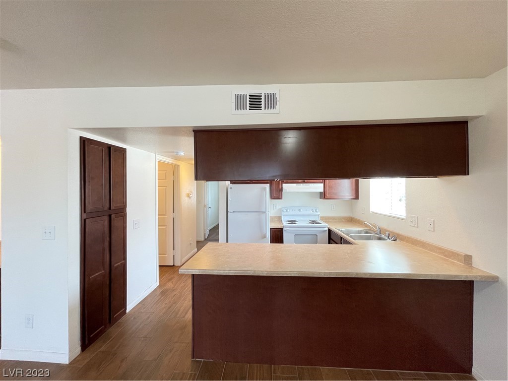 Kitchen with a wide pass-through breakfast bar, dark wood cabinets, and a sink beneath a window.