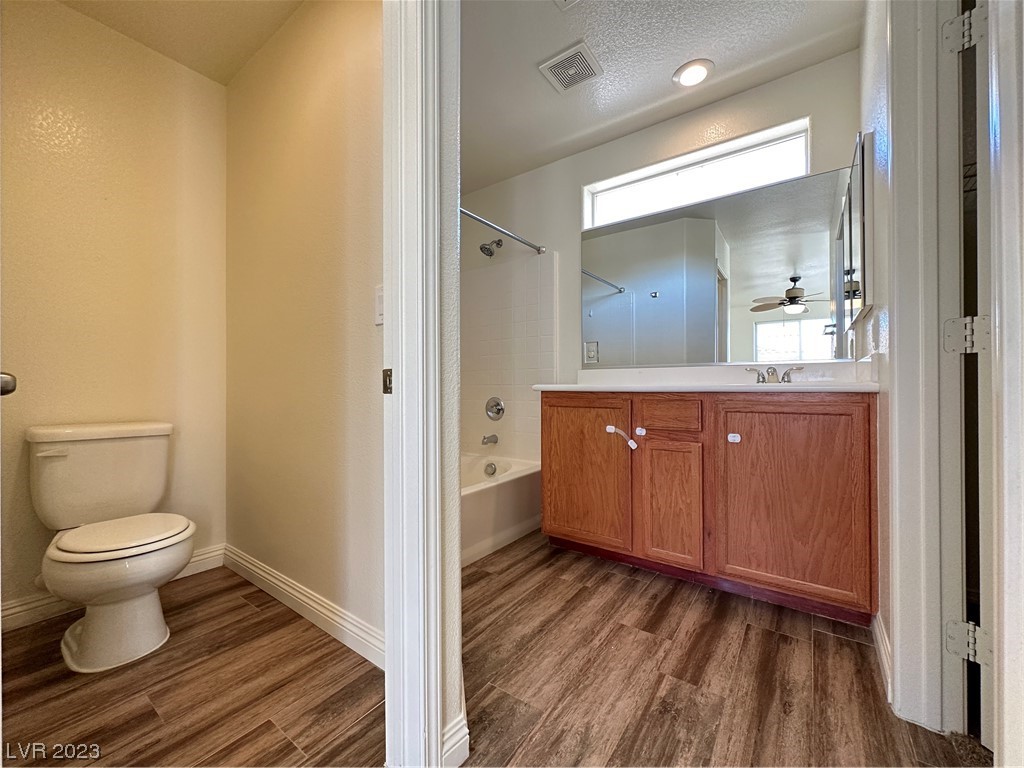 Bathroom with a wood vanity and large mirror, viewed from the separate toilet alcove.