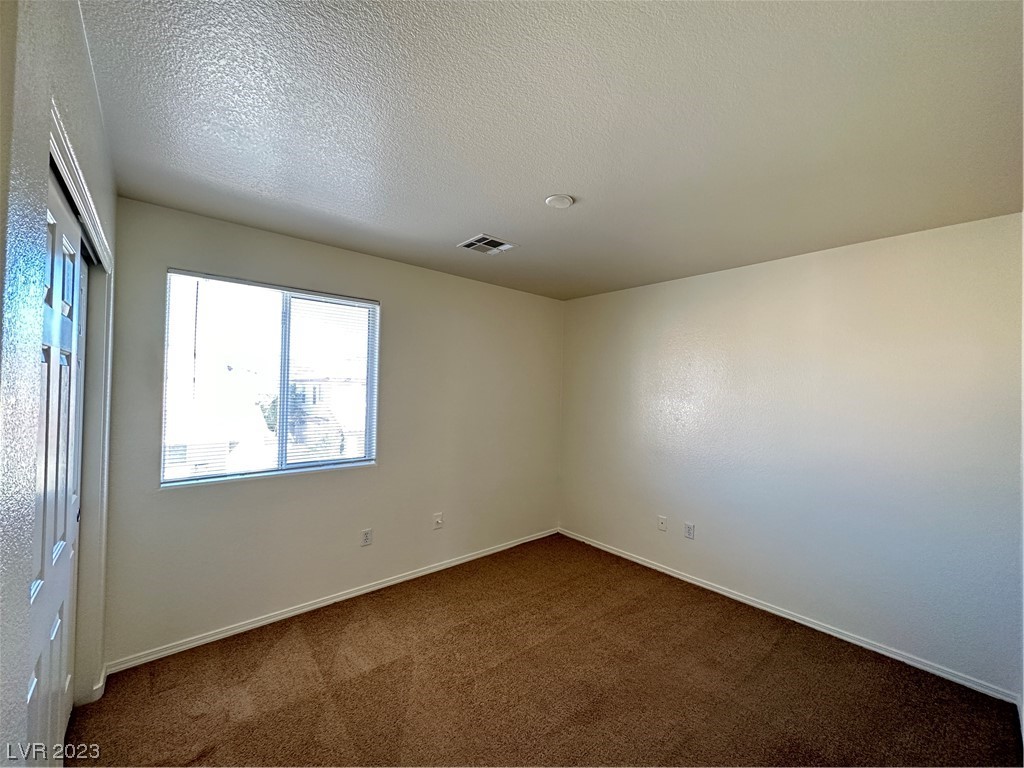 Empty carpeted room with a window and light-colored walls.