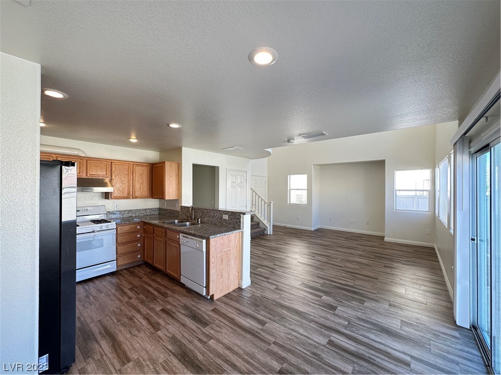 Open-plan kitchen and living area with granite counters, wood cabinets, and sliding glass doors.