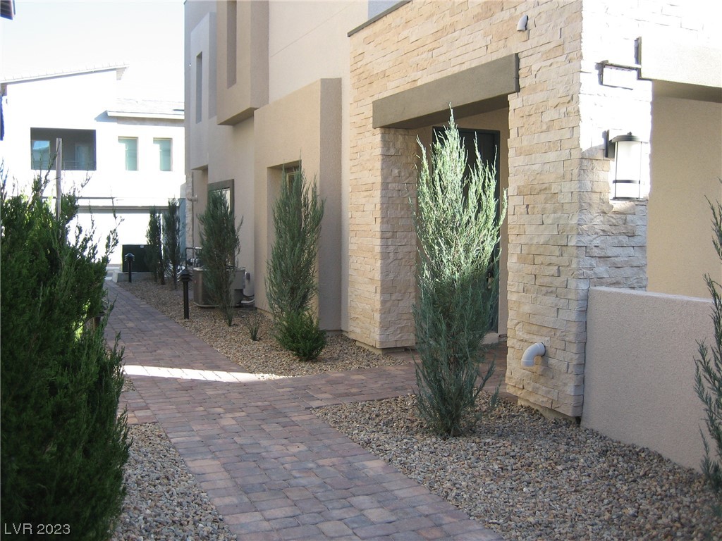 Home entry with a stone-clad surround, brick walkway, and gravel landscaping.