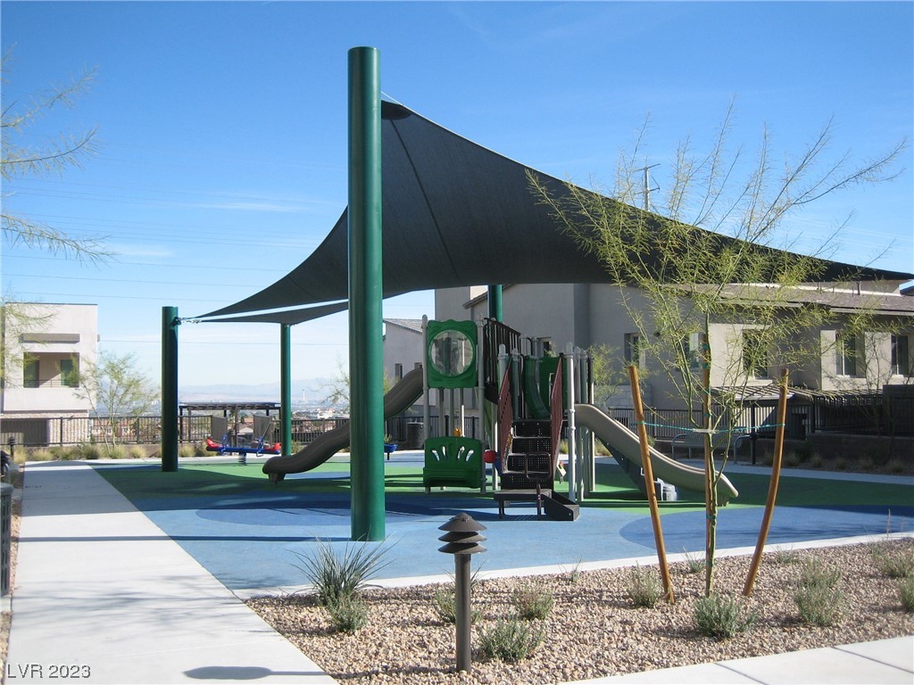 Community playground with colorful play equipment beneath a large shade canopy.
