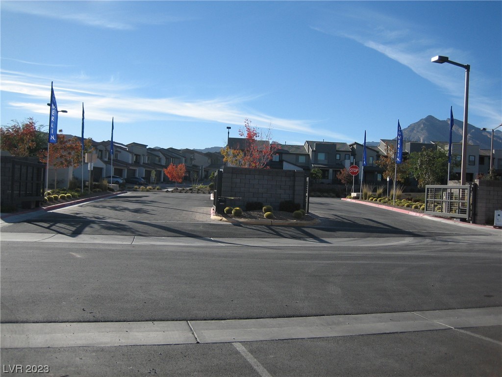 Residential development entrance with modern homes, Merlin banners, and mountains in the background.