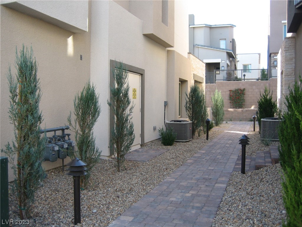 Courtyard walkway between stucco residences, with a brick-paver path and gravel landscaping.