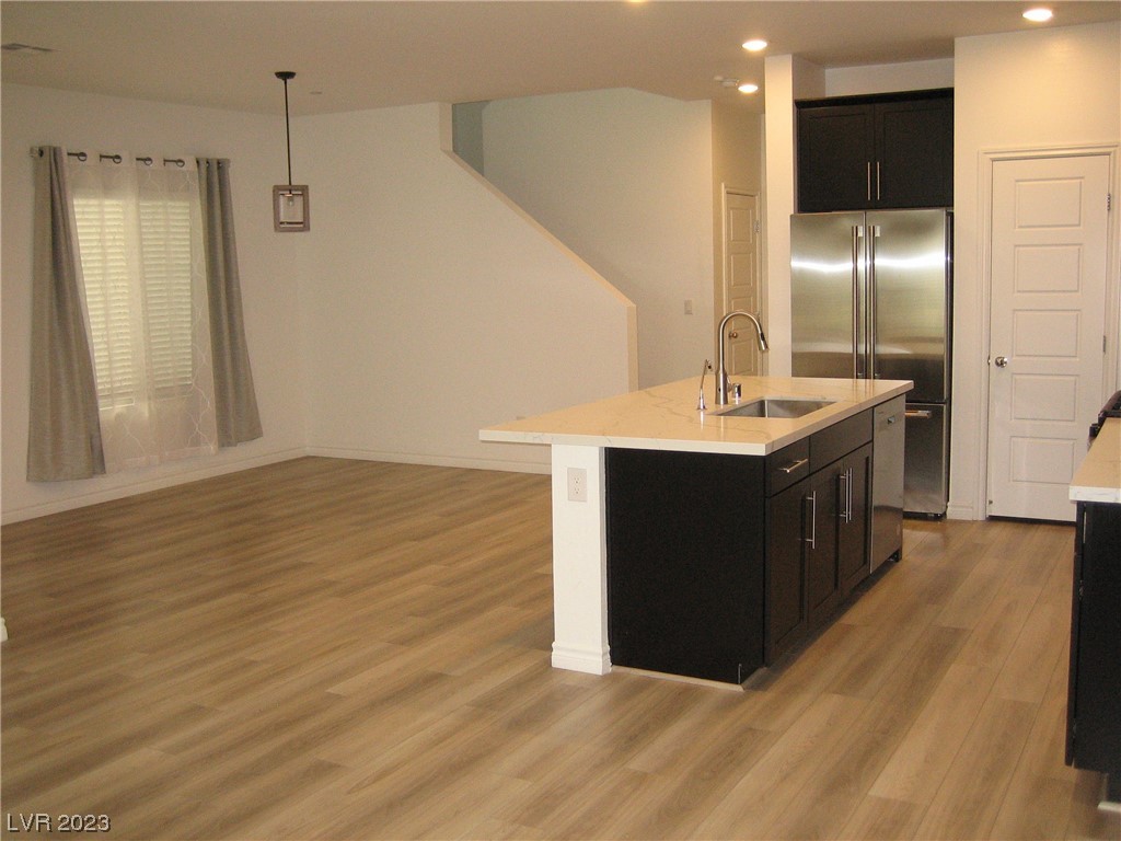Open kitchen with a dark-cabinet island, white countertop, and stainless steel refrigerator.