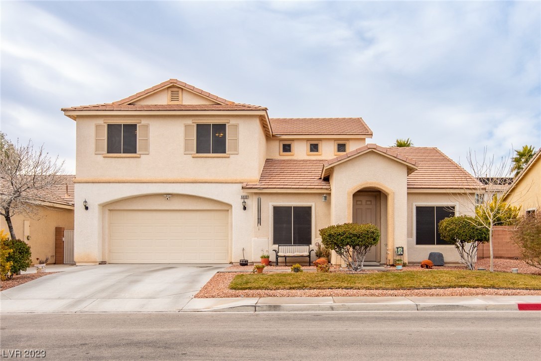 Two-story stucco home with tiled roof, double garage, and landscaped front yard.