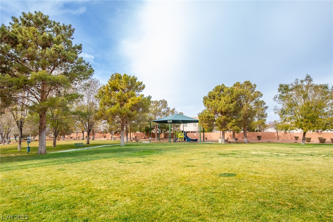 Neighborhood park with a covered playground and broad grassy lawn.