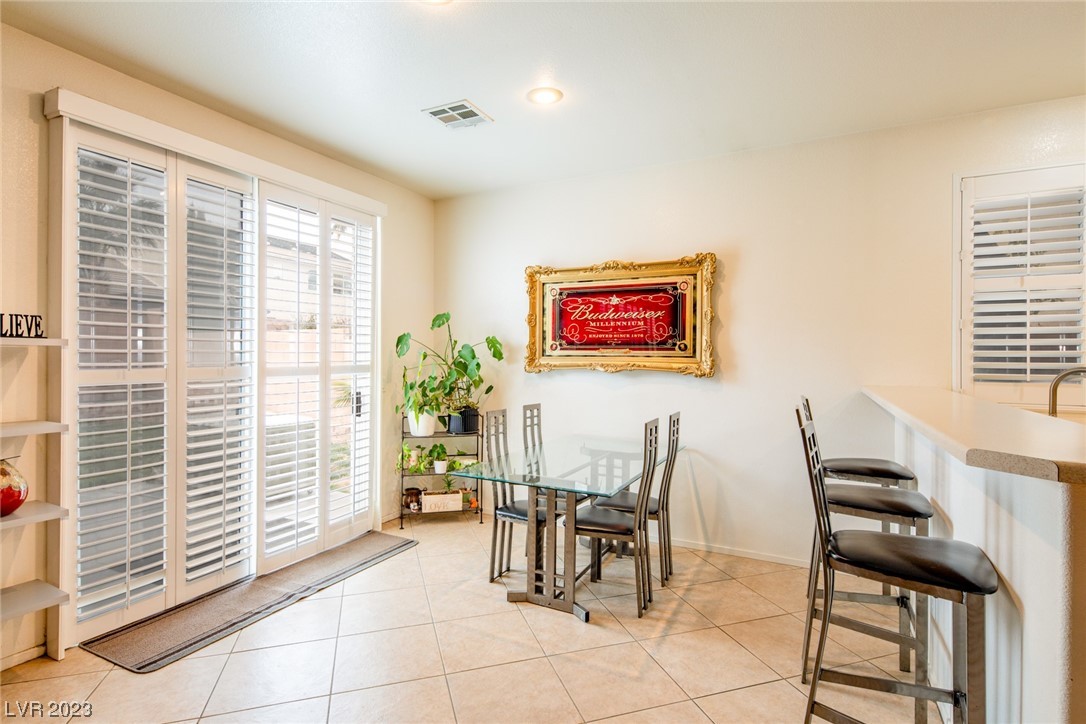 Dining area with a glass table, shuttered windows, and breakfast bar with stools.