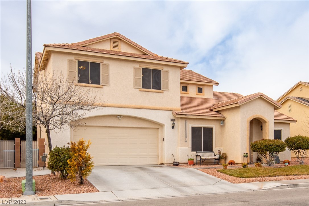 Two-story stucco home with a tile roof, double garage, arched entry, and wide driveway.