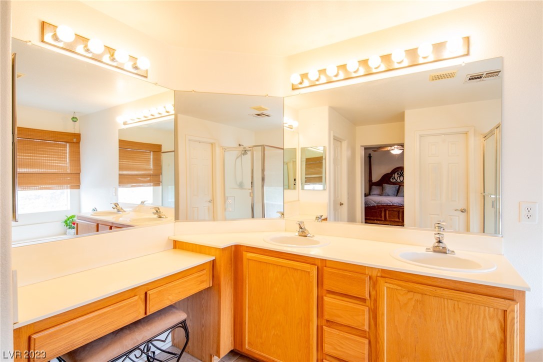 Bathroom with a double-sink vanity, wood cabinets, and expansive mirrors.