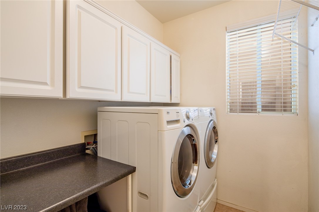 Laundry room with front-loading washer and dryer, white cabinets, and a dark countertop.