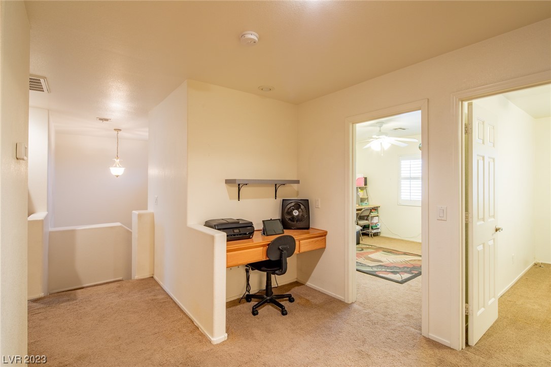 Upstairs landing with a built-in desk and chair beside open doorways to adjoining rooms.