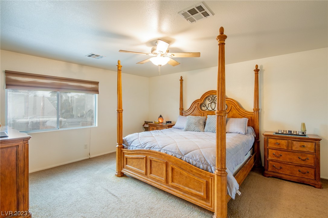 Bedroom with a carved wooden four-poster bed, matching dressers, and a wide shaded window.