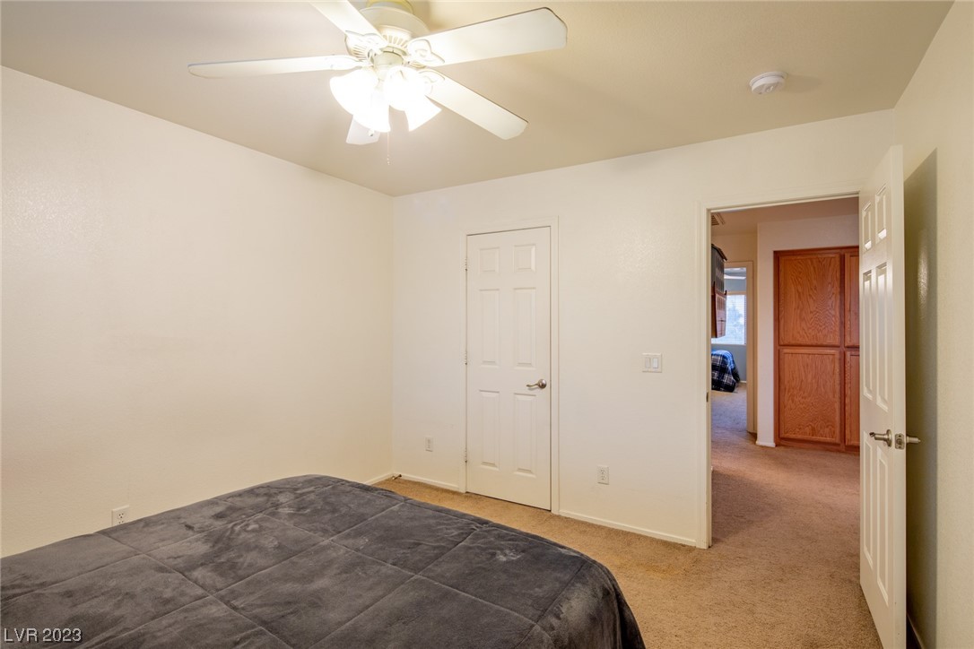 Bedroom with a dark gray bed, ceiling fan, and open doorway to a hallway.