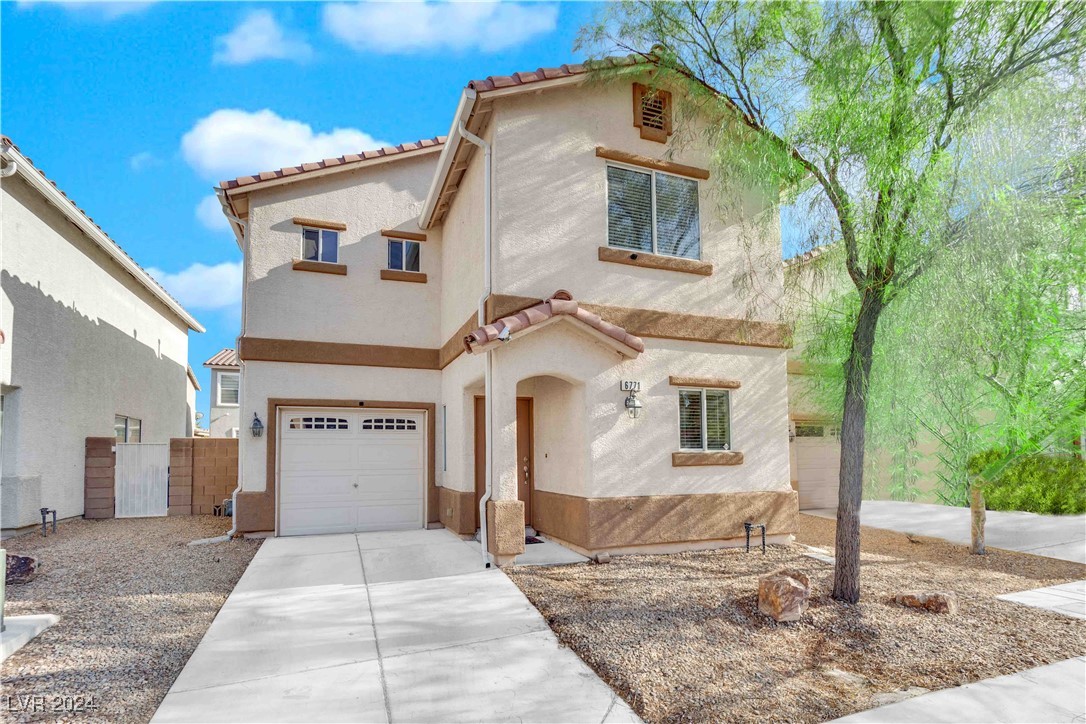 Two-story stucco house with an attached garage, tile roof, and gravel front landscaping.