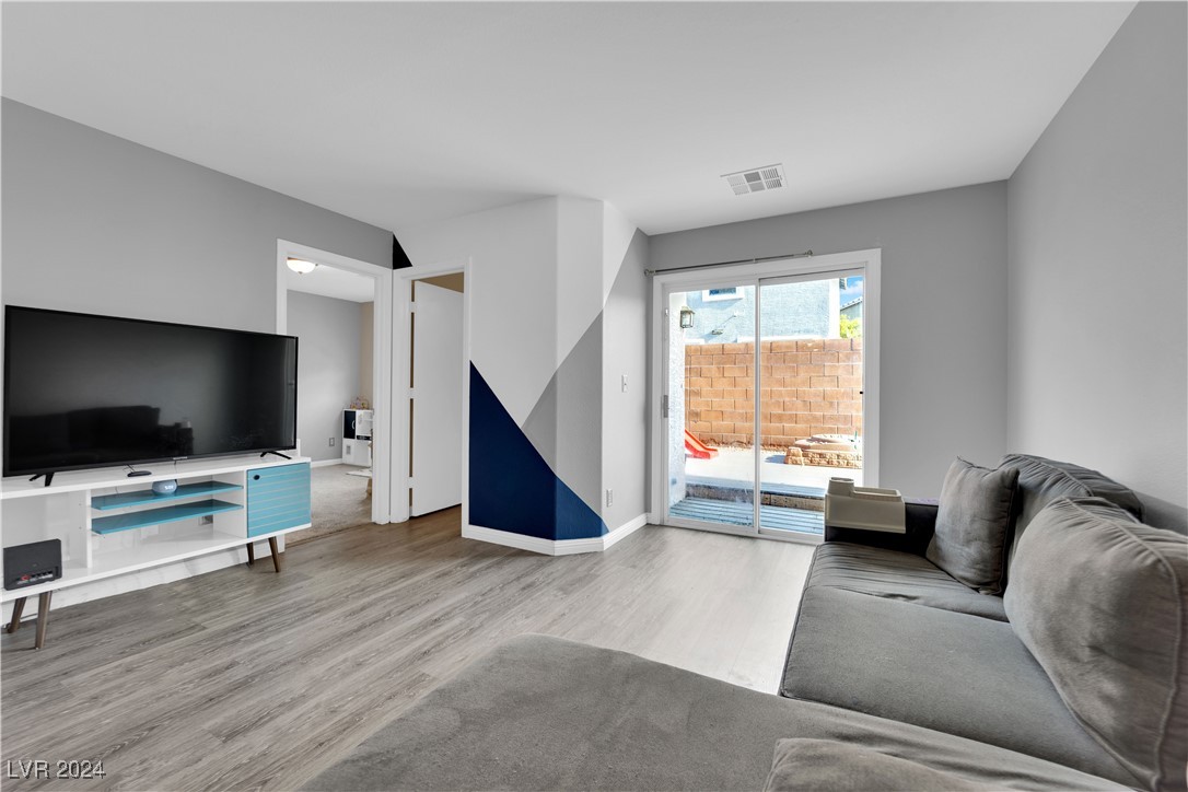 Furnished living room with a gray sectional, geometric accent wall, and sliding glass doors to a patio.