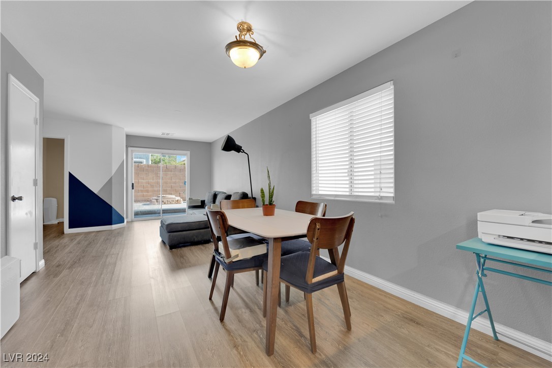 Dining area with a white table and wood chairs beside a sliding glass door to the patio.