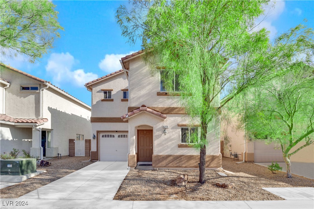 Two-story stucco home with an attached garage, gravel landscaping, and leafy trees in front.