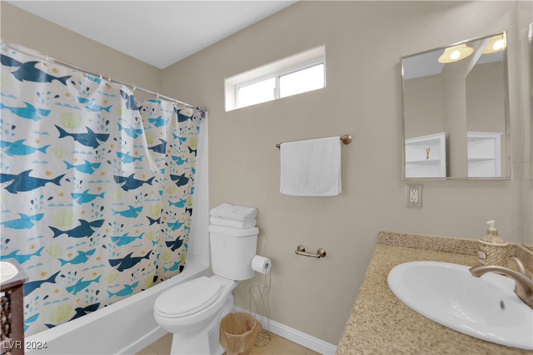 Bathroom with a whale-patterned shower curtain, toilet, and granite vanity.
