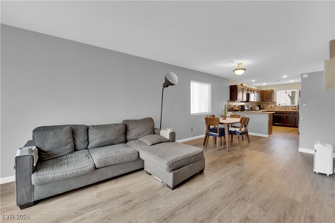 Open-plan living room with gray sectional sofa, dining table, and kitchen beyond.