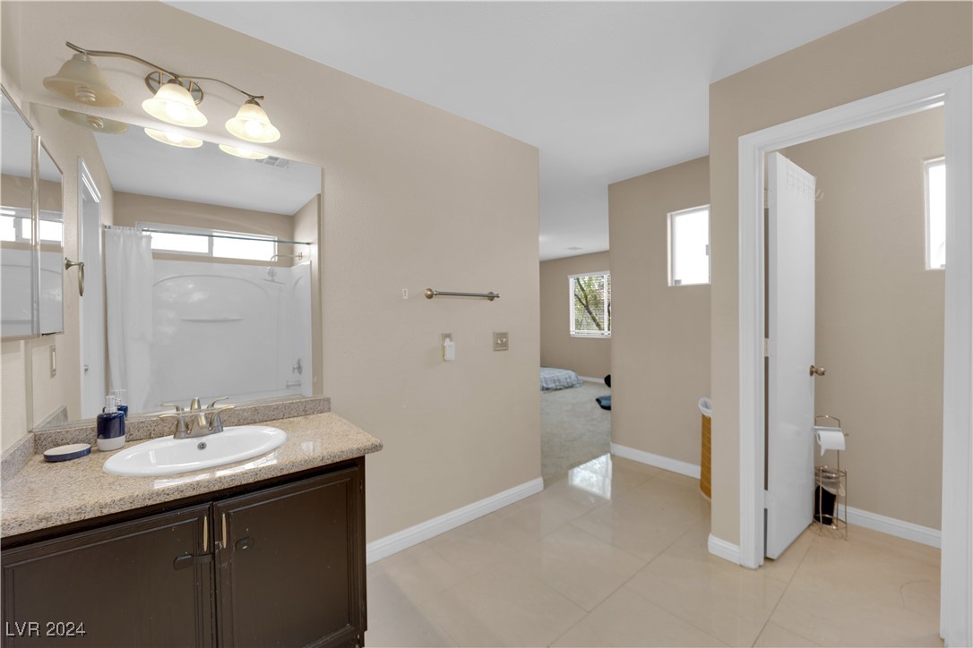 Bathroom with a granite vanity, large mirror, and shower-tub beside an open bedroom doorway.
