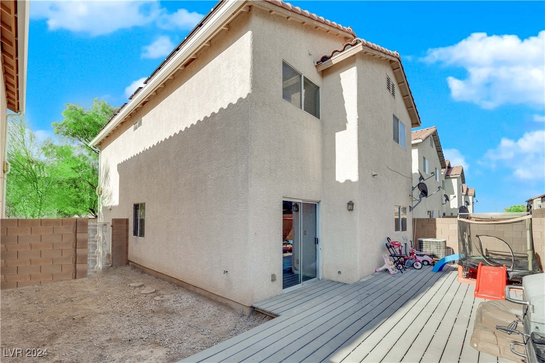 Two-story stucco home with a raised backyard deck and fenced, desert-landscaped yard.