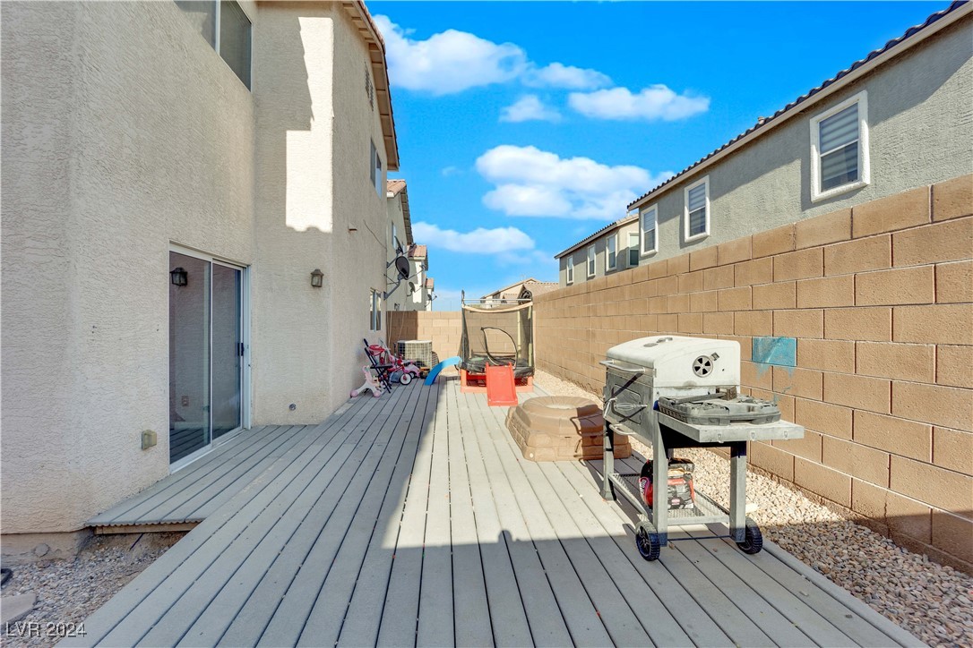 Backyard deck with a barbecue grill, block wall, and children’s toys.