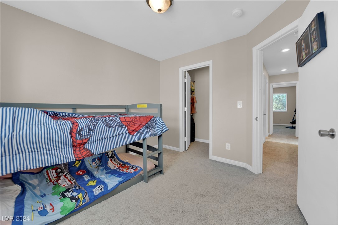 Bedroom with a gray bunk bed, colorful children’s bedding, and carpeted floor.