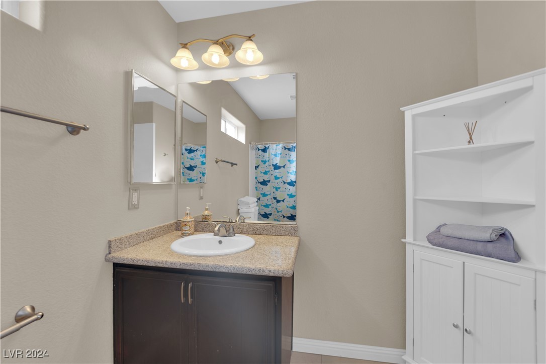 Bathroom vanity with a speckled countertop, large mirror, and white built-in shelving.
