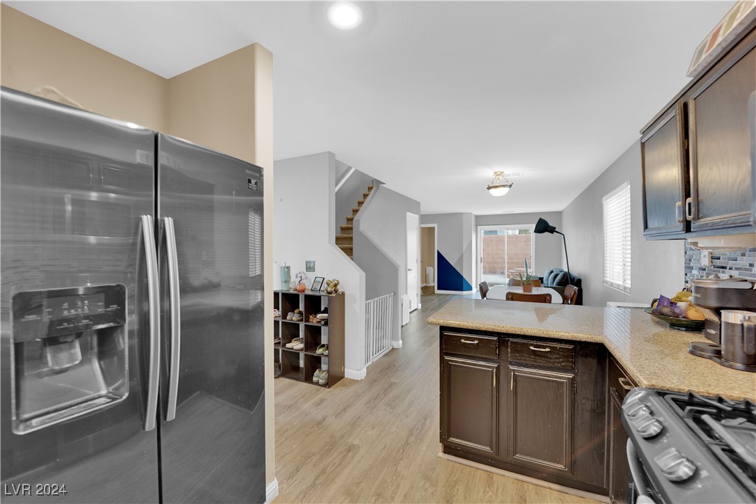 Kitchen with stainless-steel appliances and granite counters opening toward the dining and living areas.