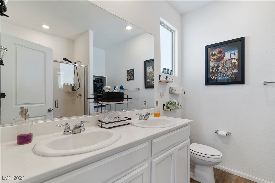 Bathroom with a white double-sink vanity, glass shower, and colorful framed artwork.