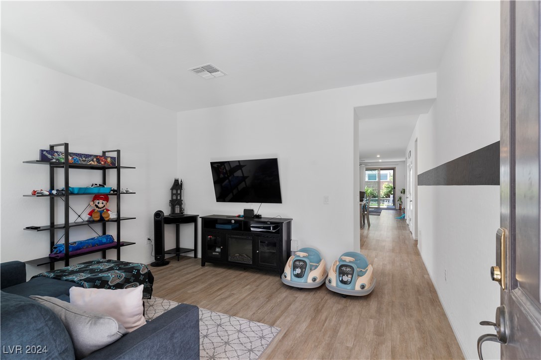 Living room with a wall-mounted TV, black media console, shelving, and blue sofa.