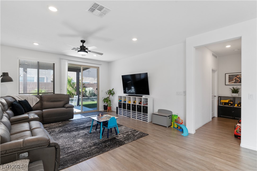 Living room with leather sofas, a wall-mounted television, and sliding doors opening to a fenced backyard.