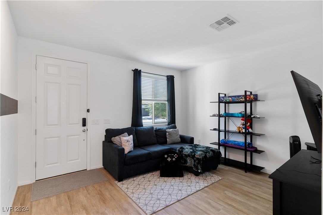 Furnished living room with dark sectional, patterned rug, and shelving displaying toys and collectibles.