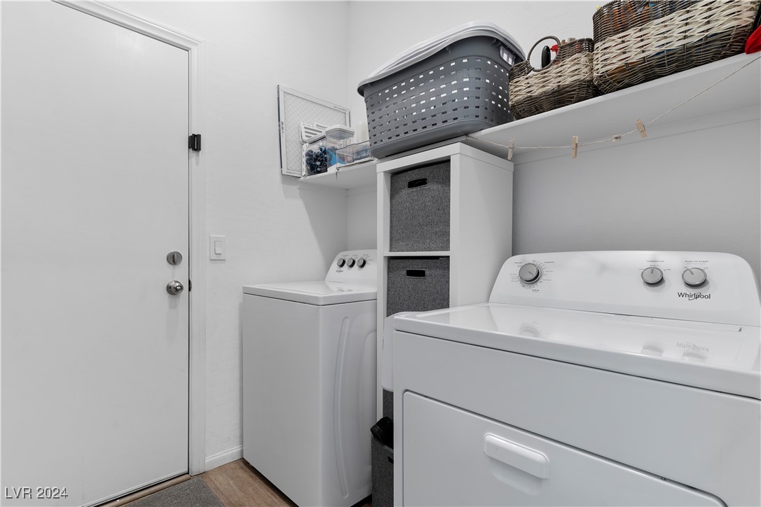 Laundry room with white washer and dryer, overhead baskets, and a tall storage cabinet.