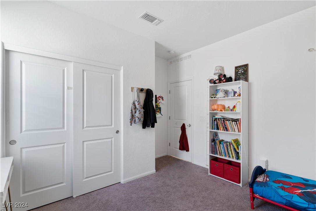 Child’s bedroom with a bookcase of books and toys and a blue superhero bed.