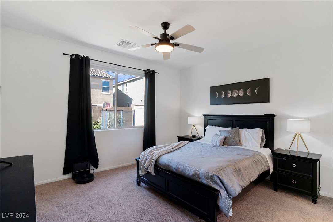 Staged bedroom with a black bed, gray bedding, moon-phase wall art, and a window framed by black curtains.