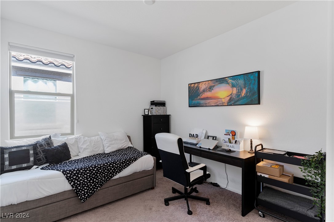 Bedroom with a white daybed, black desk and chair, and colorful wave artwork.