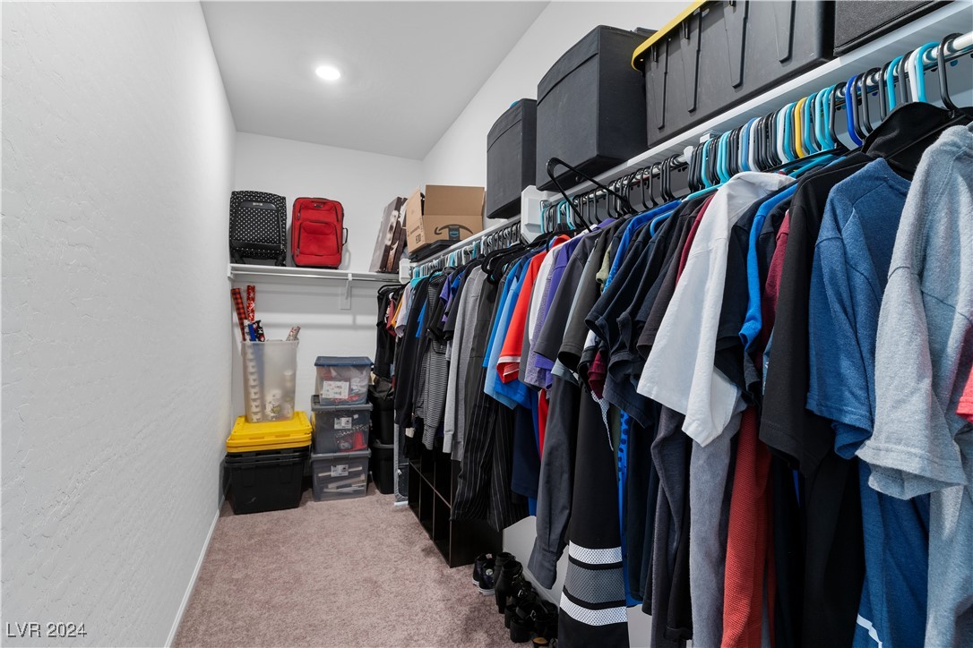 Walk-in closet with clothing racks, upper storage bins, and clear plastic drawers.