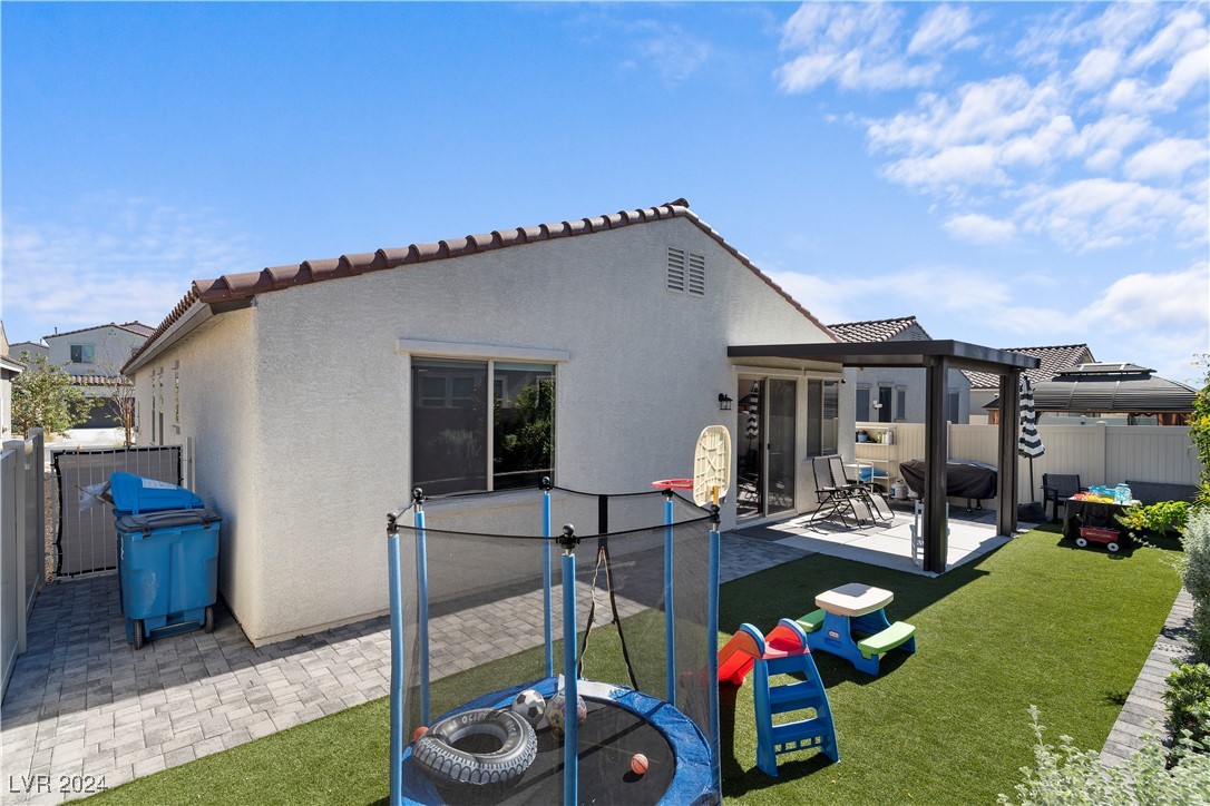 Home’s backyard with a covered patio, artificial turf, and children’s play equipment.