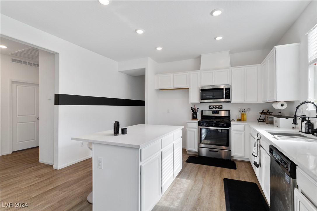 White kitchen with a large island, stainless steel appliances, and a black accent stripe.
