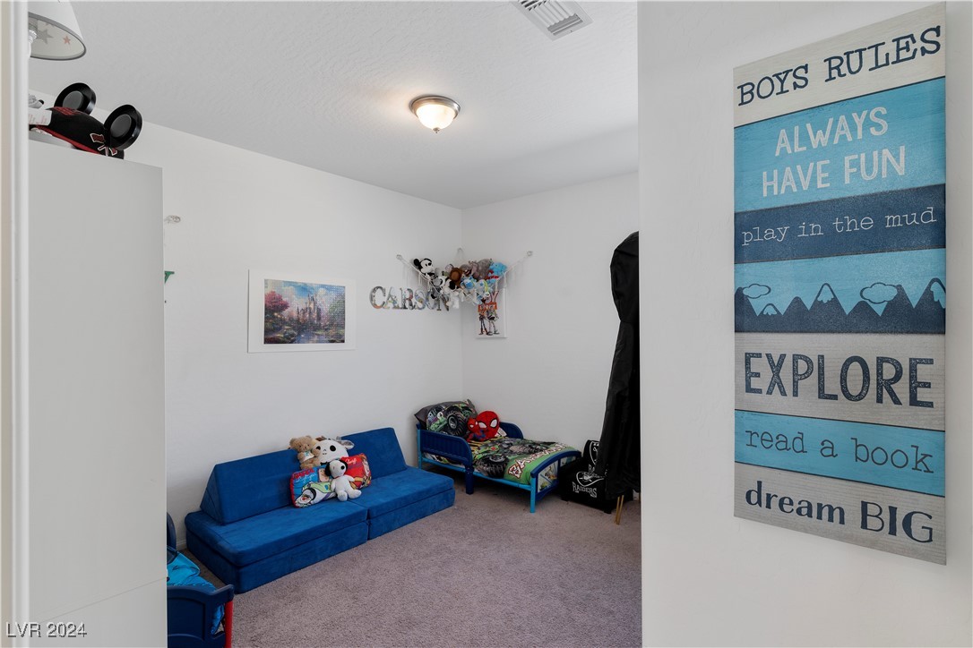 Children’s bedroom with a blue sofa, small bed, stuffed animals, and a large “Boys Rules” wall sign.