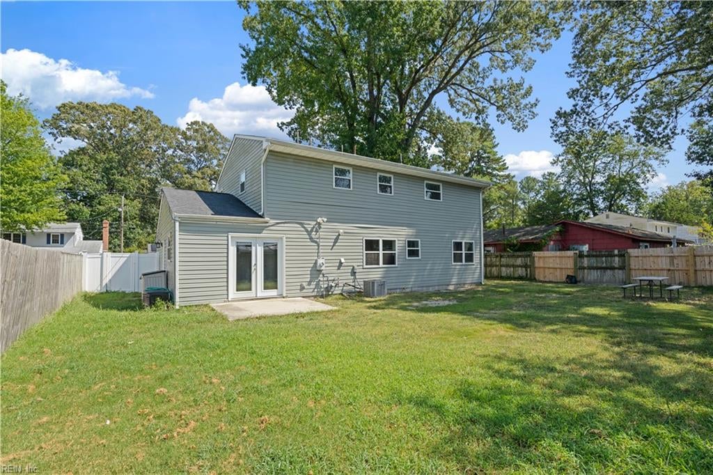 Two-story gray house and fenced backyard with mature trees.