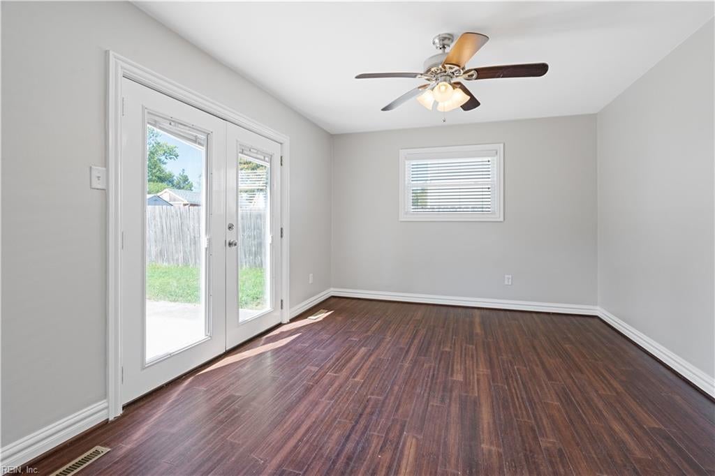 Empty room with dark wood-look floors, a ceiling fan, and glass doors to the yard.