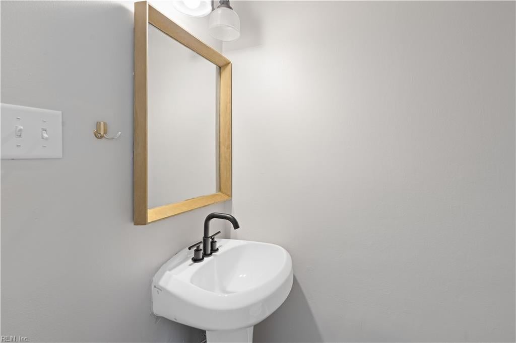 Bathroom sink with a black faucet beneath a wood-framed mirror.